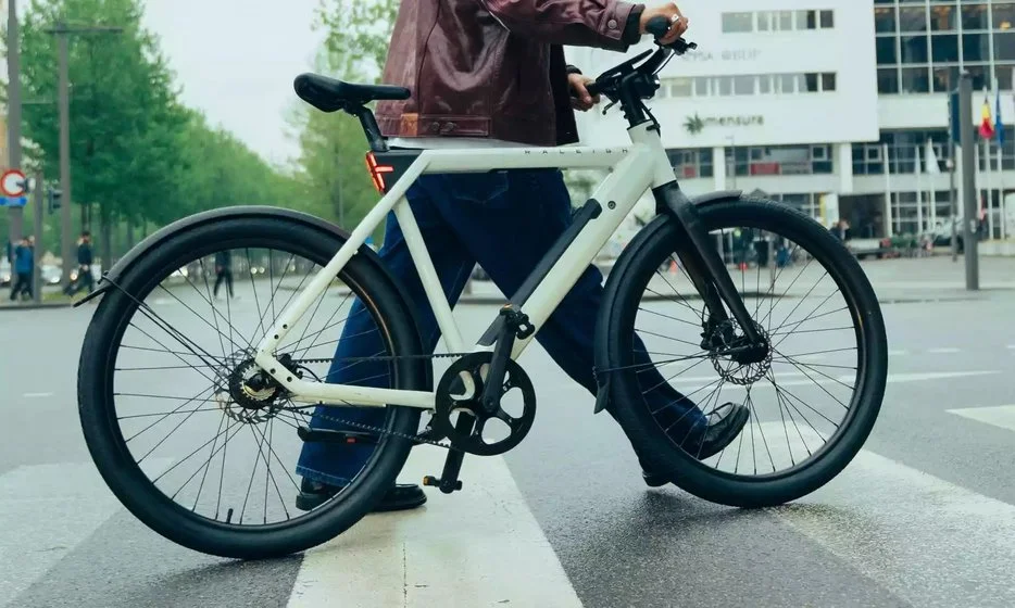 Iemand loopt met een witte e-bike over een zebrapad